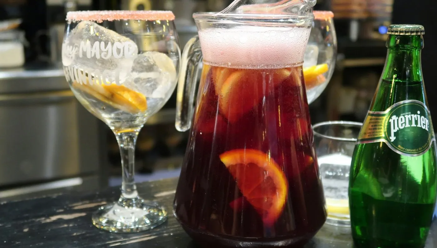 Sangrijas krūka ar apelsīnu, citronu ripiņām un ledu galdā